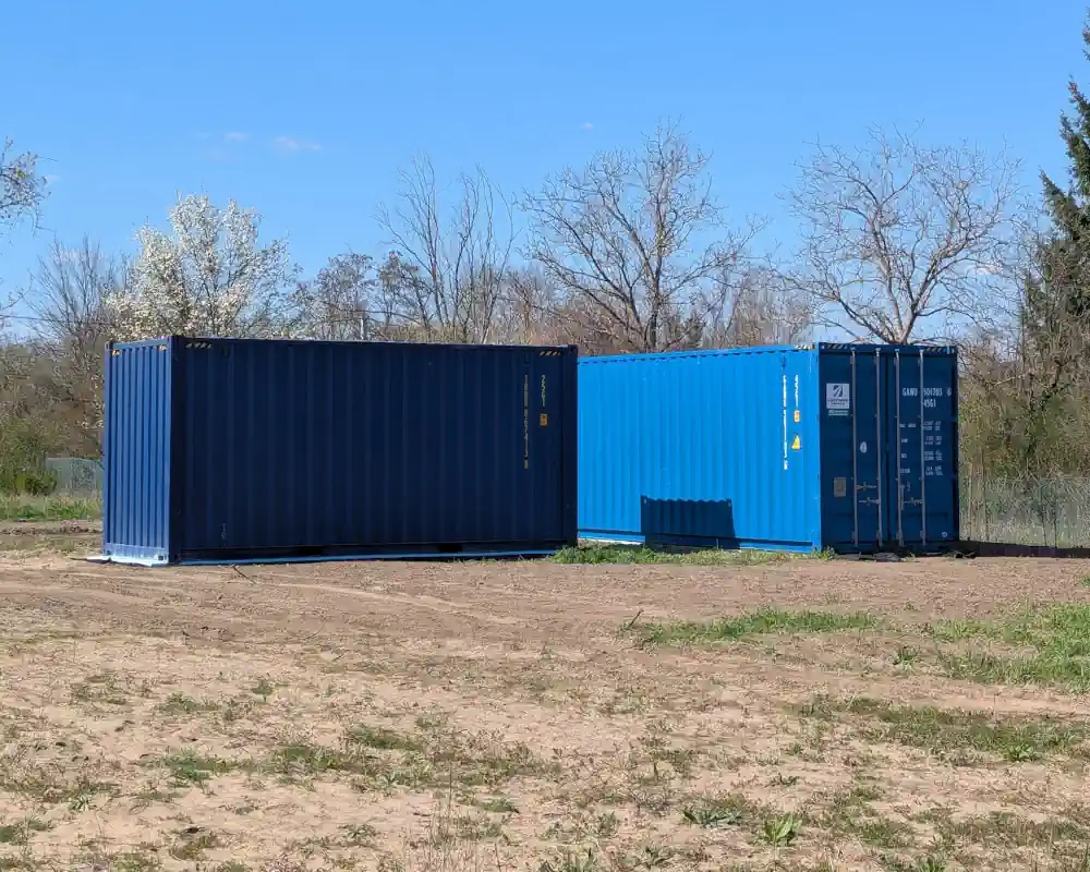 Two finished builds on site — from the outside, ordinary blue shipping containers